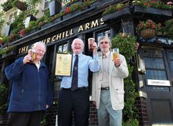 A picture of Chairman Les Maggs (left), Gerry O'Brian (centre) manager of the Chirchill Arms, and John Cryne (London Reginal Chairman) outsite the Churchill Arms with the Pub of the Year certificate. .